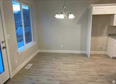 Unfurnished dining area featuring light wood-style floors and a chandelier