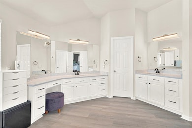 Full bathroom with wood finished floors, two vanities, and high vaulted ceiling