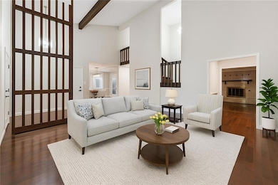 Living area with a towering ceiling, dark wood finished floors, and beam ceiling