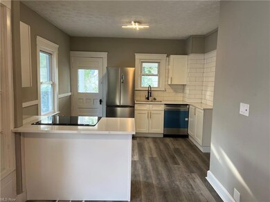 Kitchen featuring white cabinetry, a textured ceiling, stainless steel appliances, hardwood floors, light countertops, and backsplash