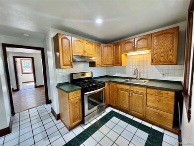 Kitchen with stainless steel range with gas stovetop, tasteful backsplash, brown cabinets, dark countertops, and light tile patterned flooring