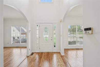 Foyer with wood finished floors and crown molding