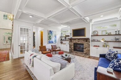The Living Room is both Stylish and Inviting, featuring a Classic Brick Fireplace, Custom Built-Ins, and Coffered Ceilings.