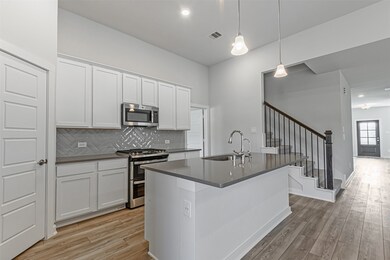 Designer touches include white farmhouse cabinets, quartz countertops, high-end subway tile, pendant lighting, and stainless steel appliances, including slide-in range with gas cooktop.