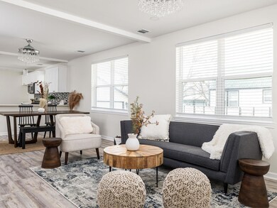 Living area with baseboards, visible vents, beam 