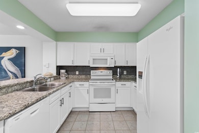 Kitchen featuring white appliances, white cabinets, decorative backsplash, and recessed lighting