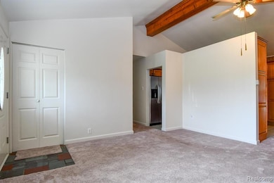 Unfurnished bedroom featuring stainless steel fridge, light carpet, ceiling fan, and a closet