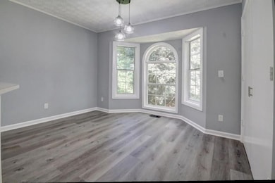 Unfurnished dining area with ornamental molding, wood finished floors, and a textured ceiling