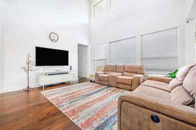 Living room with wood finished floors, a high cei