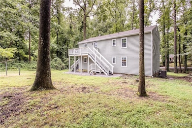 Back of house with stairs, a deck, a yard, and vie