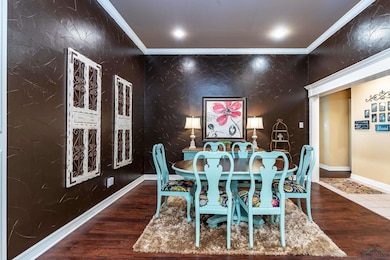 Dining room featuring crown molding, wood finished floors, recessed lighting, and an accent wall