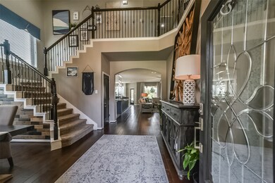 This is an inviting entryway with a grand staircase and elegant hardwood floors, leading into a spacious, well-lit open-concept living area.