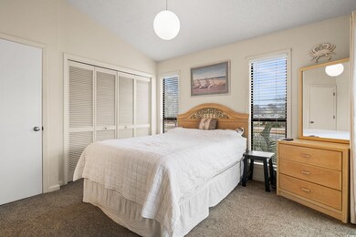 Bedroom with vaulted ceiling, light colored carpet