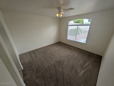 Unfurnished room featuring a ceiling fan, dark col