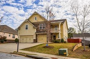 View of front facade featuring an attached garage, concrete driveway, a balcony, and a front yard