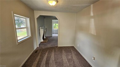 Hall with a textured ceiling and dark carpet