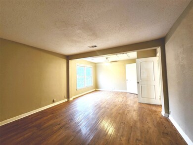 Empty room featuring wood finished floors, a textured ceiling, a ceiling fan, and a textured wall