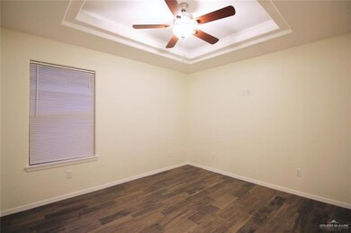 Unfurnished bedroom with a raised ceiling, dark wood-type flooring, a closet, and a ceiling fan