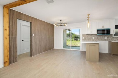 Kitchen featuring stainless steel microwave, light wood finished floors, visible vents, and backsplash