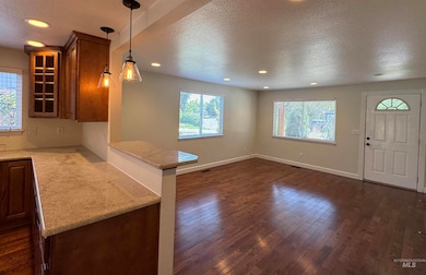 Kitchen with a textured ceiling, dark wood-style flooring, glass insert cabinets, recessed lighting, and a peninsula