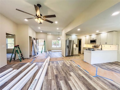 Kitchen with tasteful backsplash, open floor plan, stainless steel appliances, light countertops, and recessed lighting