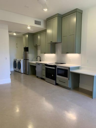 Kitchen featuring stainless steel range oven, separate washer and dryer, dishwasher, refrigerator, and backsplash