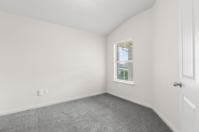 Carpeted spare room featuring lofted ceiling and 