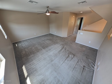 Carpeted empty room featuring ceiling fan and base