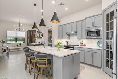 Open floor plan featuring an amazing kitchen with oversized island, walk-in pantry with custom built in shelving and additional cabinet space, natural gas stove and cooktop, custom backsplash and designer lighting.