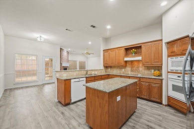 Kitchen featuring brown cabinets, backsplash, a peninsula, open shelves, and recessed lighting