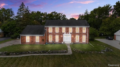 Colonial house featuring a front yard, brick siding, and driveway