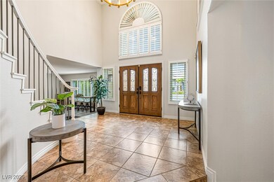 Foyer with a high ceiling, light tile patterned flooring, and stairway