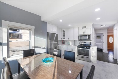 Kitchen featuring white cabinets, decorative backsplash, glass insert cabinets, stainless steel appliances, and a sink