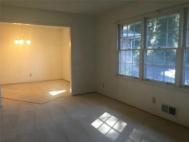 Carpeted empty room featuring a chandelier