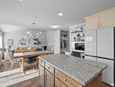 Kitchen featuring light brown cabinets, freestanding refrigerator, a kitchen island, dark wood-type flooring, and open floor plan