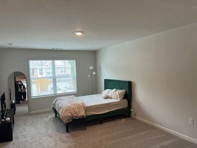 Carpeted bedroom featuring arched walkways and baseboards