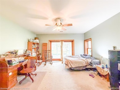 Carpeted primary bedroom with access to outside, and a ceiling fan