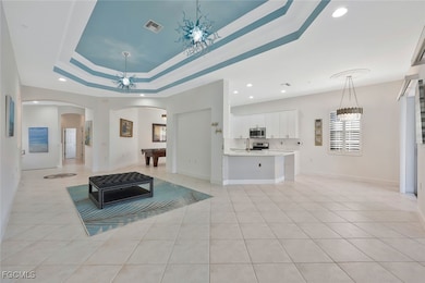 Living area featuring a chandelier, billiards table, light tile patterned floors, a tray ceiling, and recessed lighting