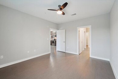 Bedroom with ceiling fan, baseboards, and dark wo