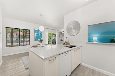 Kitchen with white dishwasher, a sink, light wood