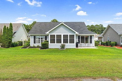 Back of house featuring a yard, roof with shingles, and a sunroom