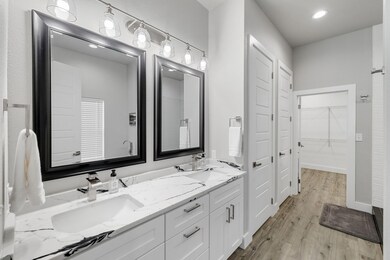 Bathroom with double vanity, light wood-style flooring, a spacious closet, and recessed lighting