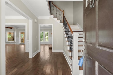 Foyer featuring ornamental molding, dark wood-type flooring, and stairway