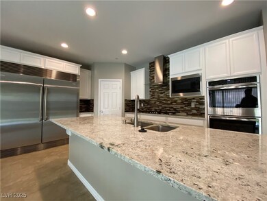 Kitchen featuring backsplash, built in appliances, white cabinetry, light stone countertops, and wall chimney exhaust hood
