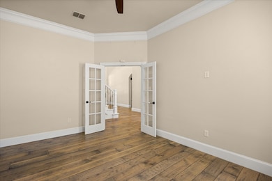 Unfurnished room featuring french doors, ornamental molding, and dark wood-style floors