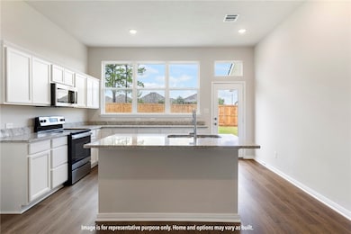 Kitchen with stainless steel appliances, light stone countertops, white cabinetry, plenty of natural light, and recessed lighting