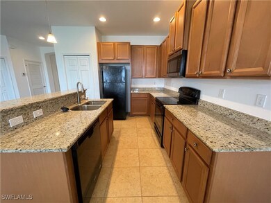 Kitchen with black appliances, brown cabinets, recessed lighting, light tile patterned flooring, and light stone counters
