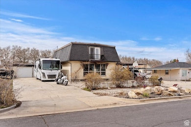 View of front of house featuring concrete driveway, fence, mansard roof, brick siding, and a garage