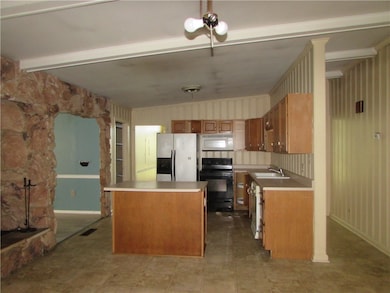 Kitchen has an island  Stone wall feature with a f