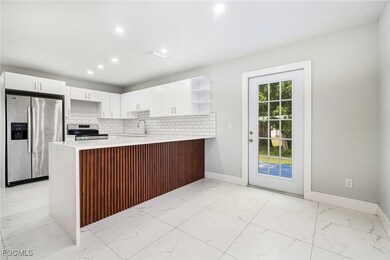 Kitchen with light marble finish flooring, stainless steel appliances, open shelves, a peninsula, and tasteful backsplash